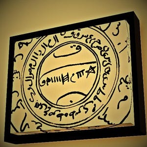 Pode incluir: Uma obra de arte emoldurada com um design circular e intrincada caligrafia preta sobre um fundo creme. A obra de arte está envolta em uma moldura preta, criando um contraste marcante. O design inclui um círculo central com texto e símbolos adicionais.