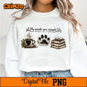 Può includere: Felpa bianca con un design grafico raffigurante una tazza di caffè, un'impronta di zampa e una pila di libri con occhiali. Il testo "My needs are simple" è sopra le immagini. La parte inferiore dell'immagine contiene il testo "Digital File PNG".