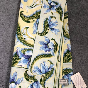 May include: A yellow tablecloth with a blue and green floral pattern. The tablecloth is folded in half and has a tag attached that says "April Cornell" and "Cornwall Prints".