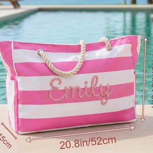 May include: A pink and white striped tote bag with the name "Emily" embroidered on the front. The bag has rope handles and side pockets. It measures 52cm long, 37cm high, and 15cm wide.