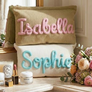 Pode incluir: Uma caneca de cer&acirc;mica branca com uma al&ccedil;a preta e o texto "But First, Coffee" em preto, com uma fonte manuscrita. A caneca est&aacute; sobre uma superf&iacute;cie branca.