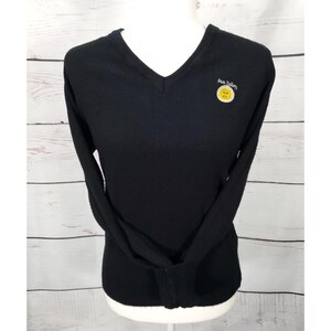 May include: Black long-sleeved v-neck sweater with the text "Sun Valley" and a yellow sun graphic.