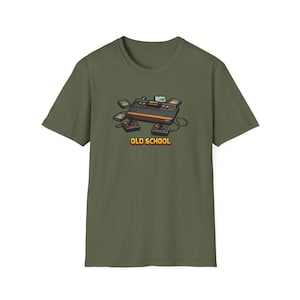 May include: Olive green t-shirt featuring a retro video game console graphic with controllers and game cartridges. The text "OLD SCHOOL" is displayed in a yellow and orange font. A nostalgic design for gamers.