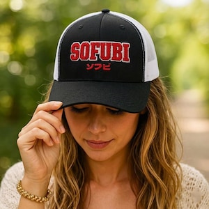 May include: Black and white trucker hat with the word "SOFUBI" in red, outlined in white, and Japanese characters below. The hat has a black brim and a white mesh back.