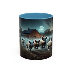 Puede incluir: Taza de cerámica con interior y borde azul. El exterior presenta una escena de granja nocturna con cerdos corriendo, un granero y una luna llena. La taza es adecuada para bebidas frías o calientes.