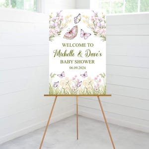 Puede incluir: Bienvenido a la fiesta de bienvenida al beb&eacute; de Michelle & Dave, un cartel con dise&ntilde;o floral y mariposas. El cartel est&aacute; en un caballete de madera y la fecha de la fiesta es el 06.09.2024.
