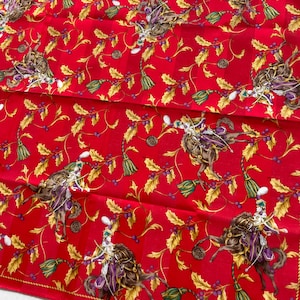 Può includere: Un foulard in seta rossa con un motivo ripetitivo di cavalieri, foglie di agrifoglio dorate, bacche viola e nappe verdi. Il design presenta un sottile sfondo a righe e la scritta CELINE PARIS stampata nell'angolo in basso a destra.