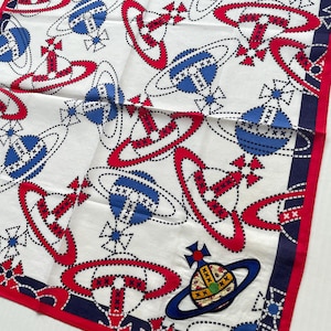 Può includere: Foulard quadrato bianco con un motivo ripetuto di globi e croci rossi e blu. La sciarpa ha un bordo rosso e un design angolare blu e bianco. È visibile una toppa con un globo blu e dettagli dorati.