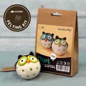May include: A needle felting kit to make two small felt owls. The kit includes wool, needles, and instructions. The owls are white with green accents and black eyes. The kit is labeled "Woolbuddy Owl Kit Needle Felting".