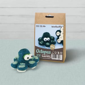 May include: A needle felting kit in a brown paper bag with a label featuring a dark teal octopus. The label includes the text Woolbuddy, Octopus Kit, and states it makes one octopus 3 to 4 inches. A finished dark teal felted octopus sits nearby.
