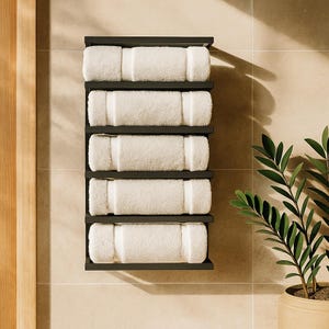 May include: A black wall-mounted towel rack with five shelves, each holding a rolled white towel. The towels are neatly arranged, creating a clean and organized look. The rack is mounted on a light-colored tiled wall, with a plant in a pot in the corner.