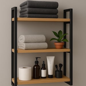 May include: A three-tiered bathroom shelf with black metal supports and light wood shelves. The top shelf holds folded dark gray towels. The middle shelf has rolled light gray towels and a potted plant. The bottom shelf displays toiletries.