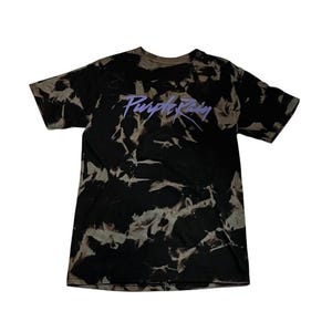 May include: A black and white tie-dye t-shirt with a purple "Purple Rain" logo printed on the front.