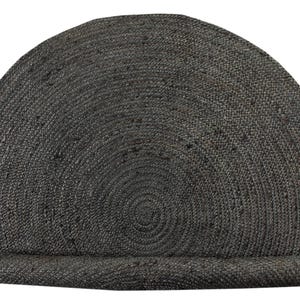 May include: A round, gray, woven jute rug with a circular pattern. The rug is rolled up and has a fringed edge.