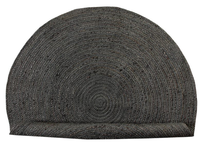 May include: A round, gray, woven jute rug with a circular pattern. The rug is rolled up and has a fringed edge.
