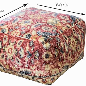 Może przedstawiać: Kwadratowa pufa z wzorem w kolorze czerwonym, beżowym i granatowym. Pufa ma wymiary 60 cm z każdej strony i 35 cm wysokości. Tkanina ma teksturowany wygląd.