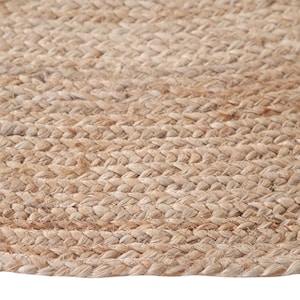 May include: A close-up of a natural fiber rug made from jute. The rug has a woven texture and a light brown color.