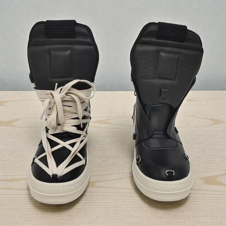 Pode incluir: Par de t&ecirc;nis pretos de cano alto com solas brancas. Um t&ecirc;nis apresenta cadar&ccedil;os creme cruzados, enquanto o outro tem z&iacute;per e detalhes met&aacute;licos. Ambos t&ecirc;m cabedais pretos acolchoados e solas brancas.