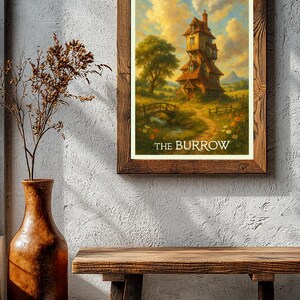 May include: A framed print of a whimsical house with a tall chimney, set in a vibrant landscape with a bridge and trees. The text "THE BURROW" is at the bottom. The frame is made of dark wood. A rustic wooden bench and a tall vase are in the foreground.