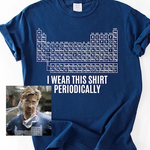 Puede incluir: Camiseta azul marino con la tabla periódica de los elementos y la frase blanca "I Wear This Shirt Periodically". Una pequeña imagen de una persona con gafas está en la parte inferior izquierda. Una camiseta gráfica con temática científica.
