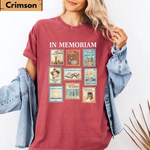 May include: Crimson red t-shirt with the words "IN MEMORIAM" above a collection of postage stamp designs. The stamps feature various themes, including "Public Broadcasting" and "Climate Research".