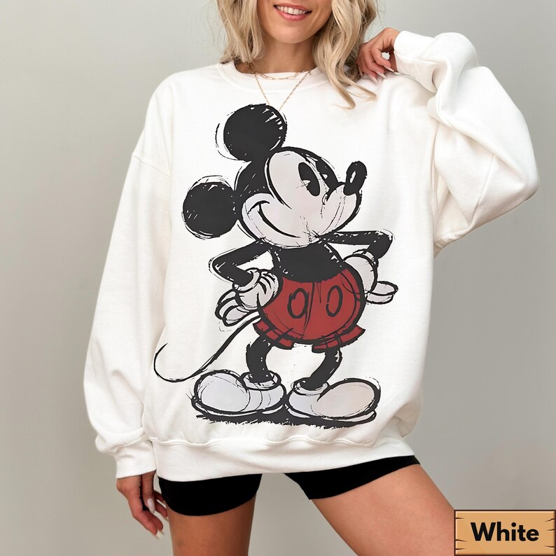 Puede incluir: Sudadera blanca con un gr&aacute;fico cl&aacute;sico de Mickey Mouse en negro, rojo y blanco. La ilustraci&oacute;n tiene un estilo vintage y esbozado. La sudadera es de cuello redondo.