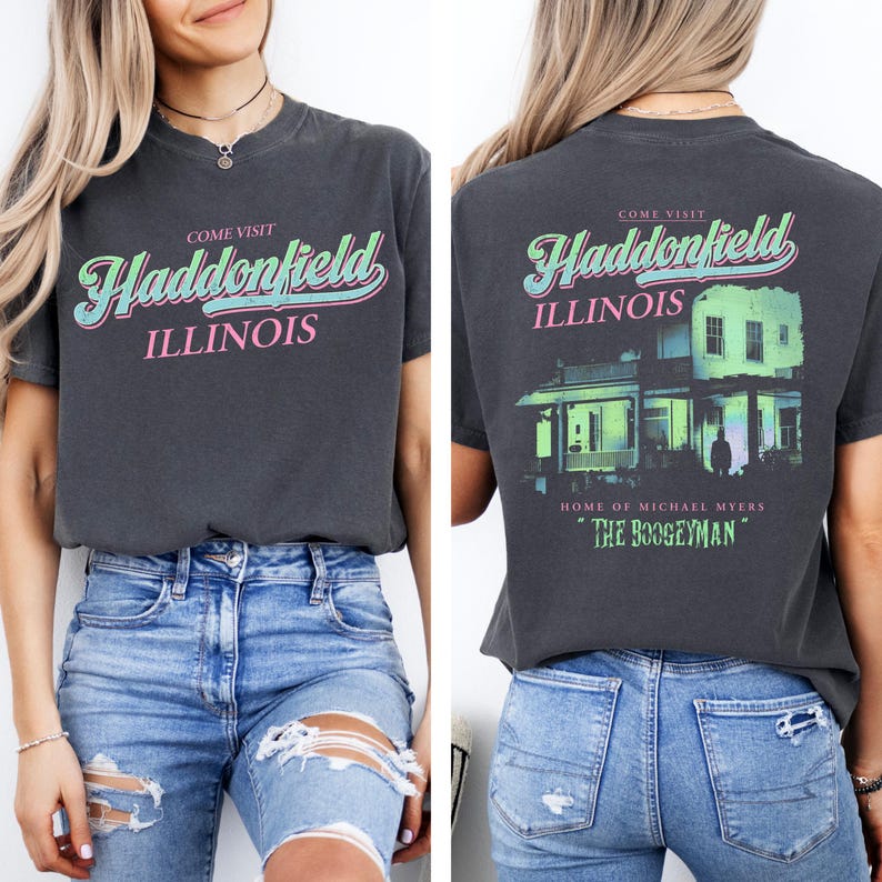May include: Dark gray t-shirt with the words "COME VISIT Haddonfield ILLINOIS" in a retro font on the front. The back of the shirt features a house graphic and the text "HOME OF MICHAEL MYERS" and "THE BOOGEYMAN".