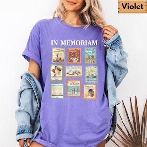 May include: A violet-colored t-shirt with the words "IN MEMORIAM" above a collection of postage stamp-style graphics. The stamps depict various themes, including "Public Broadcasting," "Vaccine Research," and "Climate Research."