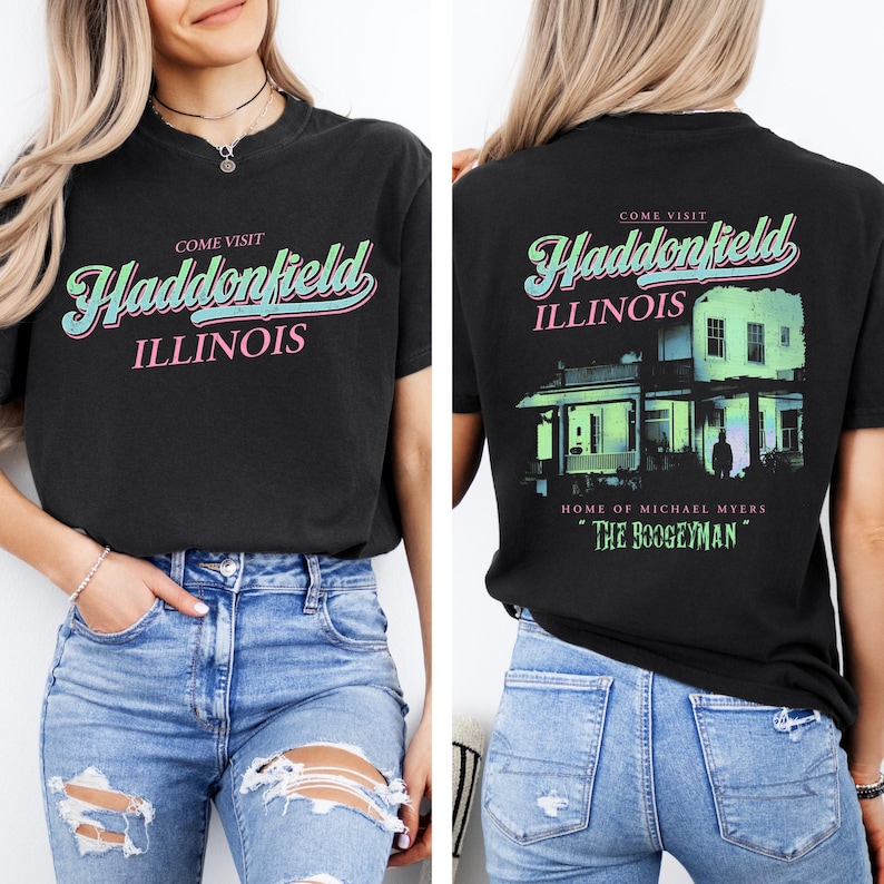 May include: Black t-shirt with the words "Come Visit Haddonfield Illinois" in a retro font on the front. The back of the shirt features a house graphic and the text "Home of Michael Myers" and "The Boogeyman."