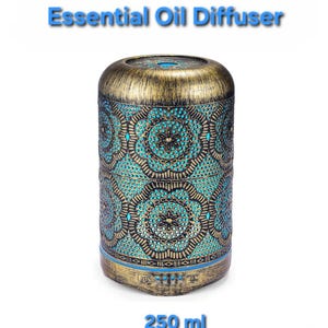 May include: An essential oil diffuser with a cylindrical shape. The top and bottom are gold-colored, while the body features a turquoise and black floral pattern. The text "Essential Oil Diffuser" is above the product, and "250 ml" is below.