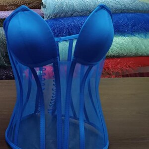 May include: A blue mesh corset with a sweetheart neckline and boning. The corset is made of a sheer fabric and has a satin lining.