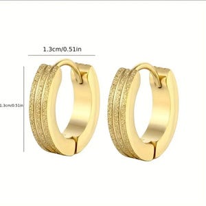 May include: A pair of gold hoop earrings with a textured surface. The earrings are 1.3 cm in diameter.