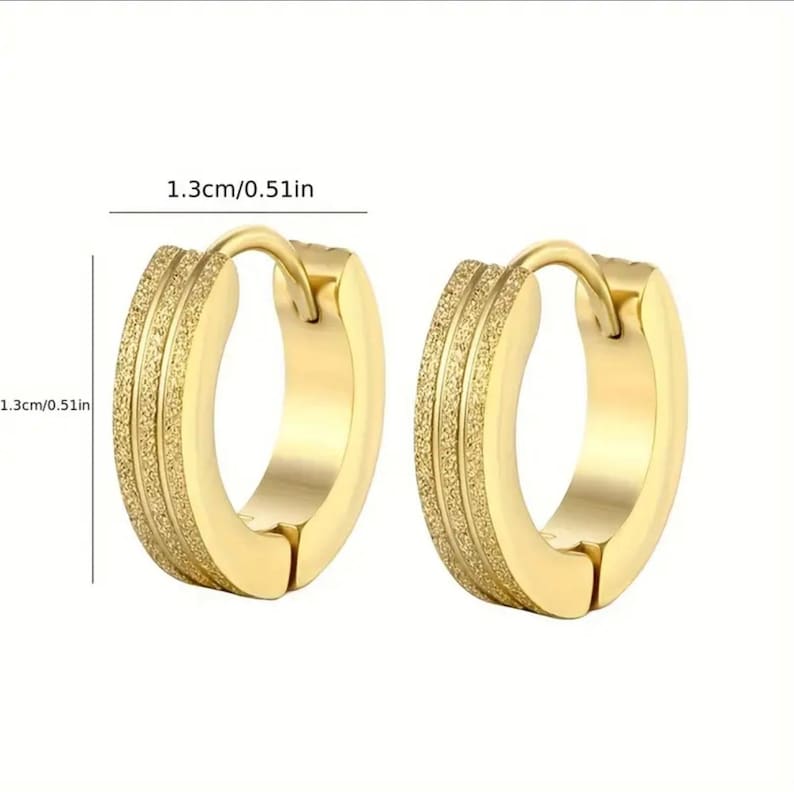 May include: A pair of gold hoop earrings with a textured surface. The earrings are 1.3 cm in diameter.