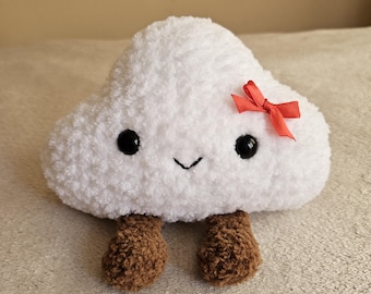 May include: A plush cloud toy with a smiling face, black eyes, and brown feet. A small red bow is attached to the cloud. The toy is made of soft, white material.