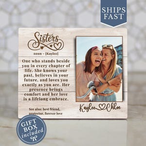 May include: Wooden photo frame with the word "Sisters" and a definition. The frame includes a photo of two smiling women. Text on the frame reads "Kaylee & Chloe". A gift box is included.