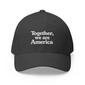 May include: A dark grey baseball cap with a curved peak. The cap has white embroidered text that reads "Together, we are America". A classic style hat, suitable for casual wear.