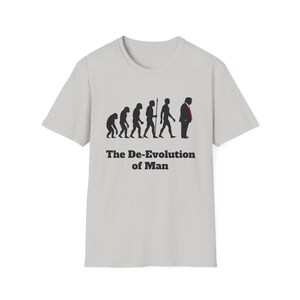 May include: Light gray t-shirt featuring a graphic of the evolution of man, culminating in a figure wearing a suit and red tie. The text "The De-Evolution of Man" is printed below the graphic in black.