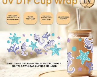 Op de afbeelding: Een doorzichtige glazen beker met een bruin deksel en een rietje. De beker is versierd met een zeepaardje- en zeesterrenontwerp. De tekst "UV DTF Cup Wrap" staat bovenaan de afbeelding.