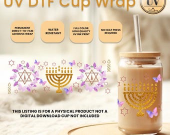 Op de afbeelding: Een glazen beker met een bamboe deksel en rietje, met een gouden glitter menorah en Davidster ontwerp, omringd door paarse vlinders en sterren. De bekerwrap is waterbestendig en vereist geen hittepers.
