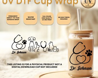 Op de afbeelding: Een heldere glazen beker met een bamboe deksel en rietje, met een zwart stethoscoop-, pootafdruk- en hartontwerp met de tekst "Dr. Johnson". De beker is ontworpen voor een UV DTF-wikkel, waterbestendig en zonder hittepers.