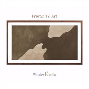 以下が含まれることがあります： テレビ画面用の額装されたアート作品。茶色とベージュの色合いで抽象的な形が描かれています。フレームは濃い木の色で、「Frame TV Art」の文字が上部にあります。「Wander Dwells」の文字も表示されています。
