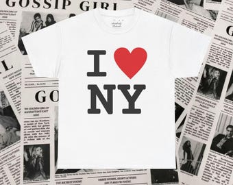 May include: White t-shirt with the iconic "I Love NY" design in black letters and a red heart. The shirt is displayed on a background of vintage newspaper pages, creating a classic and stylish look. A perfect gift for New York lovers.
