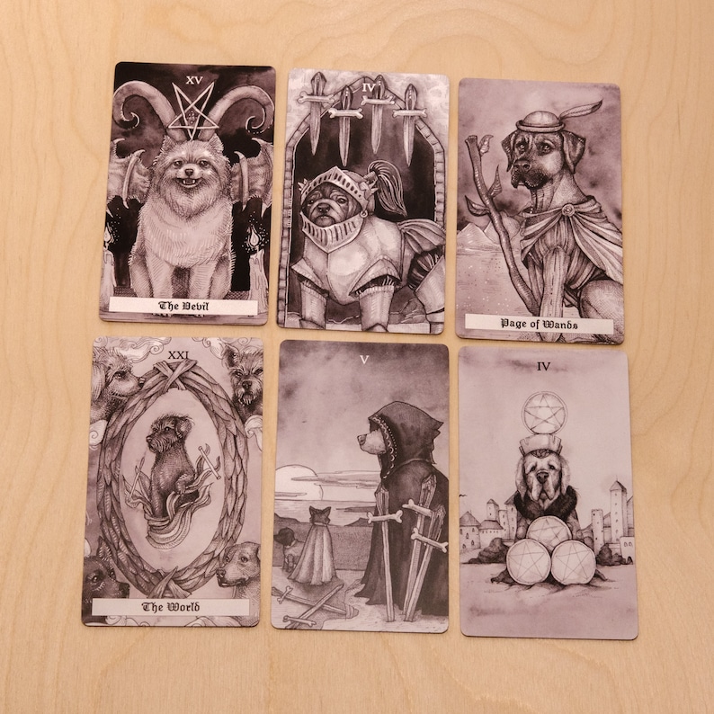 May include: A set of ten tarot cards featuring black and white illustrations of dogs. The cards are numbered with Roman numerals and have titles such as "The Devil", "Page of Wands", and "The World".