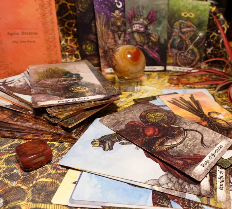 May include: A spread of tarot cards featuring illustrations of fantastical creatures and symbols. The cards are arranged on a surface with a brown and orange patterned background. The cards include "Page of Cups", "Page of Pentacles", "The Magician", and "The Star".