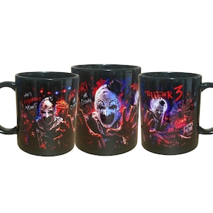 Op de afbeelding: Drie zwarte keramische mokken met grafische prints van een clownfiguur. De ontwerpen bevatten de tekst "Who's Laughing Now?", "Art the Clown" en "Terrifier 3" tegen donkere, kleurrijke achtergronden met kermisafbeeldingen en rode accenten.