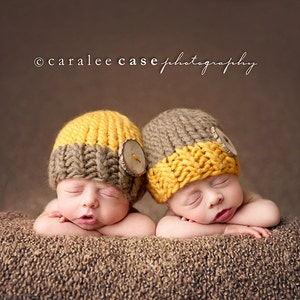 Puede incluir: Dos bebés recién nacidos con gorros de punto marrón y amarillo con botones de madera duermen sobre una manta peluda marrón. ©caralee case photography