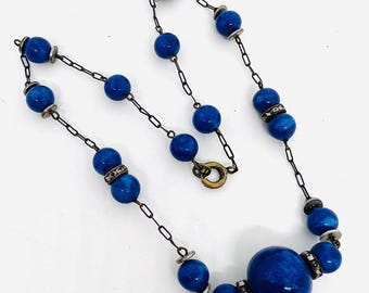 May include: A vintage blue glass bead necklace with a silver chain and silver accents. The necklace features a large blue glass bead in the center.