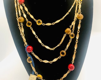 May include: A gold multi-strand necklace with red, brown, and yellow beads. The necklace is on a black display stand. The tag reads "STAR $300 plus tax."