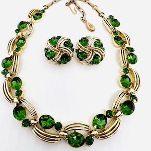 May include: A gold necklace and earrings set with large green oval-shaped stones and smaller green round stones.
