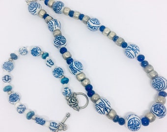 May include: A blue and white porcelain bead necklace and bracelet set with silver accents. The beads feature a traditional Chinese symbol.